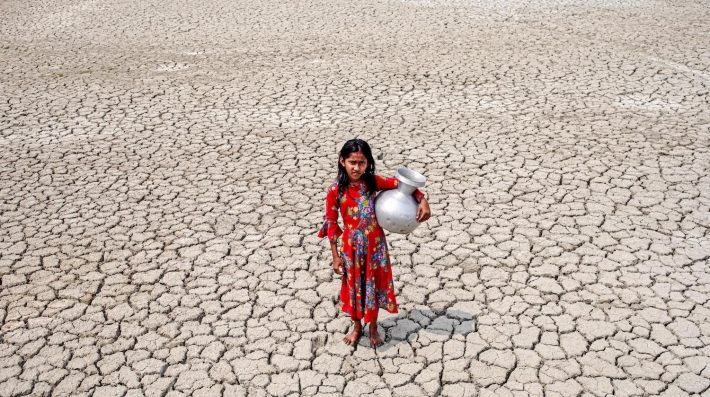 A girl walks into a deep cracks field after collecting water in Satkhira, Bangladesh. 