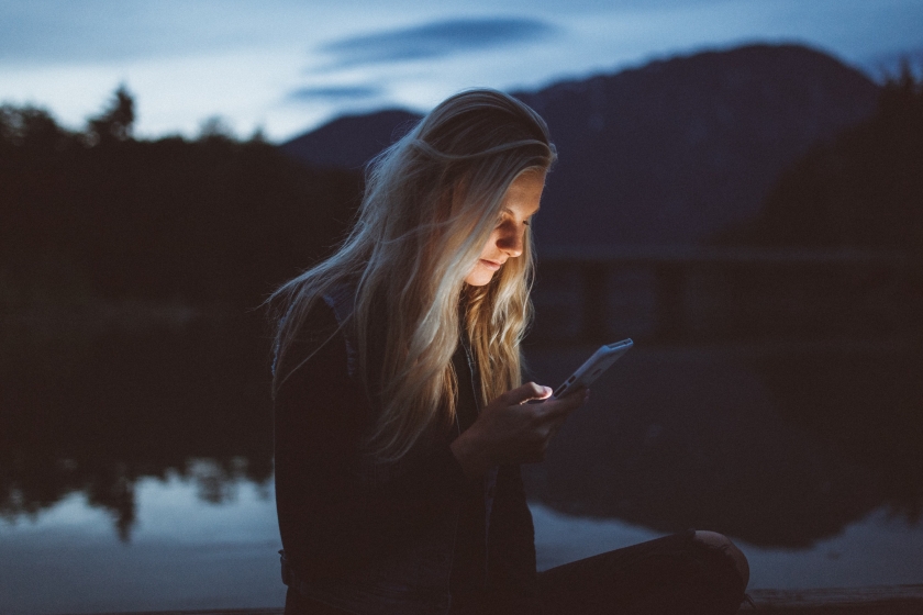 A woman typing on a phone at night.